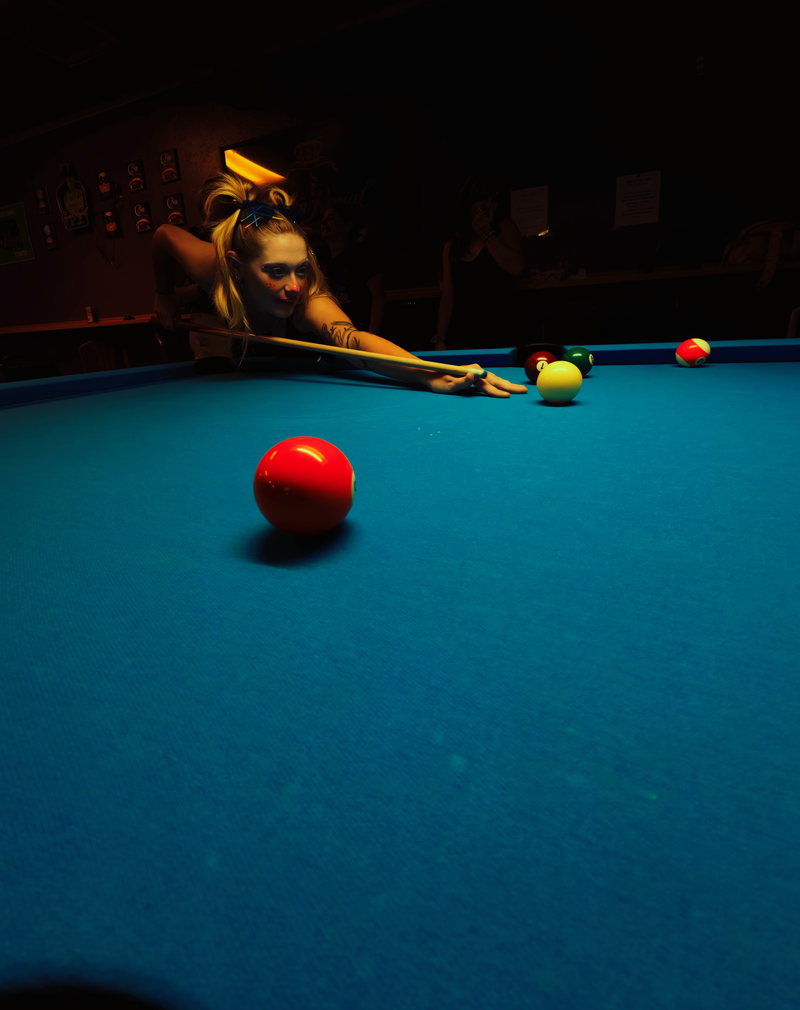 Player lining up a shot across a lit pool table